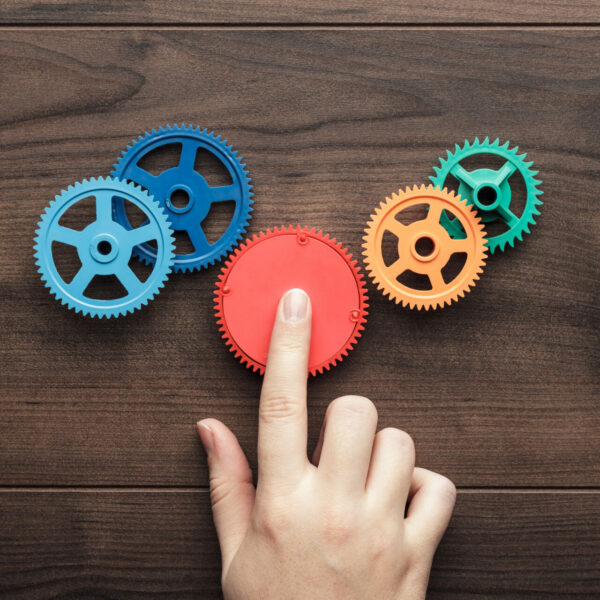 perfect solution concept. colorful gears and hand on the brown wooden background